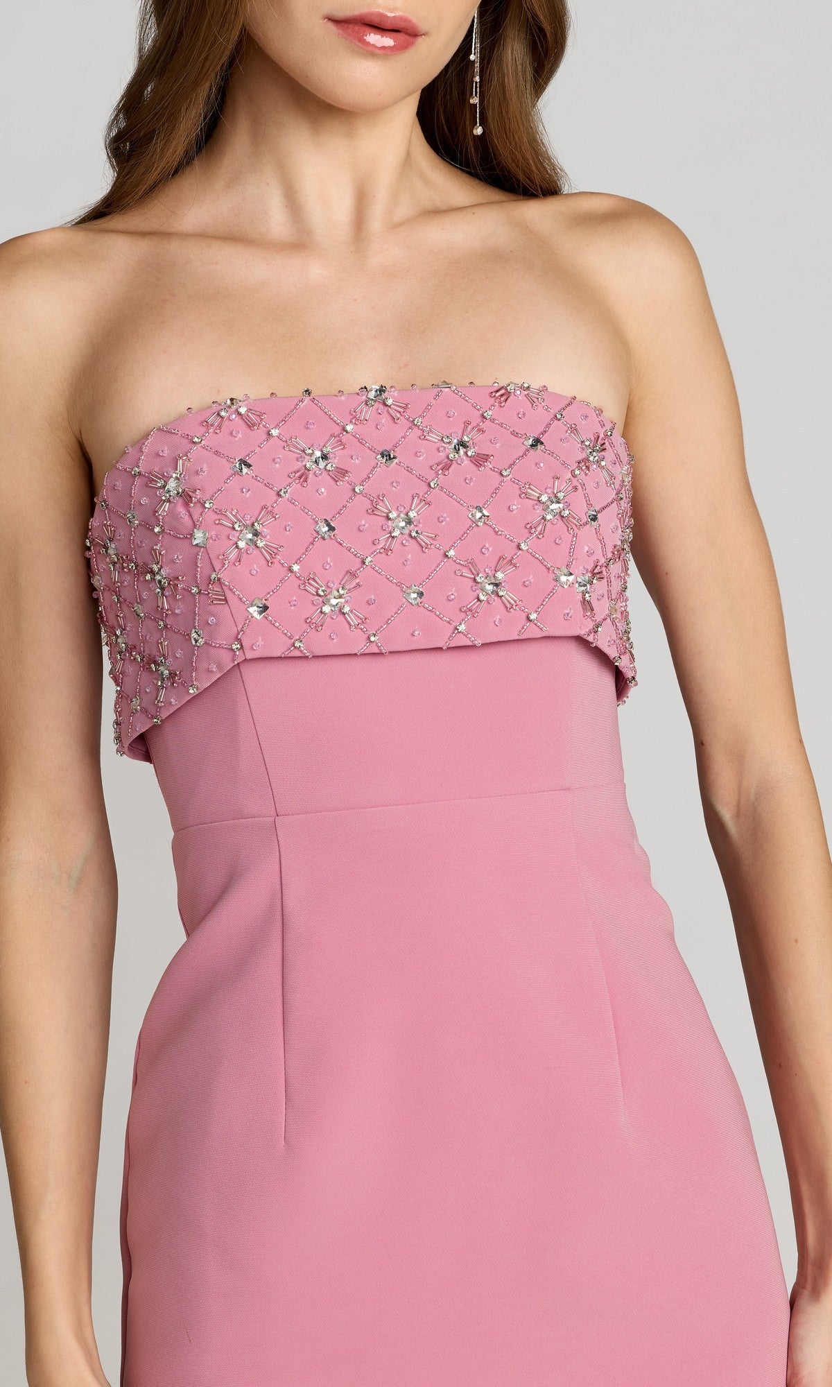 A woman wears the Mac Duggal 11883 Midi Wedding Guest Dress, a strapless pink gown with rhinestone accents and a beaded, sequined bodice, featuring a straight neckline.